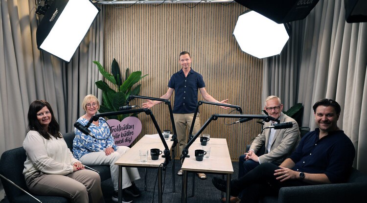 Fem personer i en studio med poddmikrofoner.