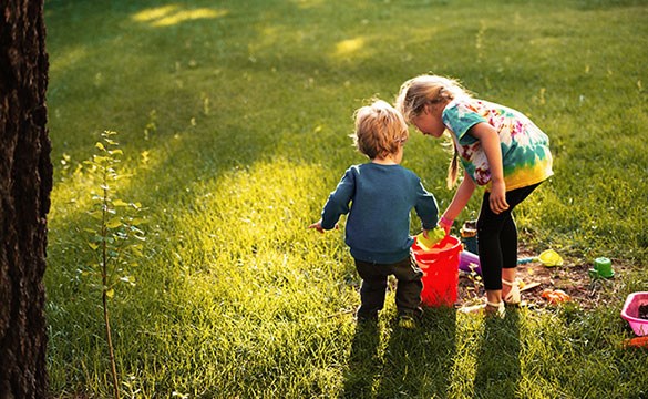 Två barn leker på en gräsmatta. Foto.