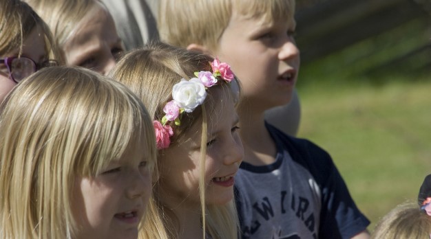 Barn med blomsterkrans i håret sjunger