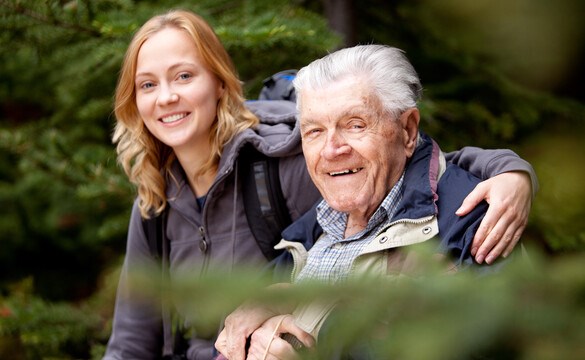 En senior man tillsammans med sitt barnbarn. Tittar in i kameran och ser glada ut. Foto.