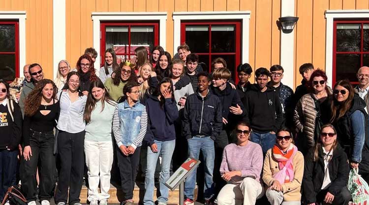 Et trettiotal unga i en gruppbild framför ett hus.