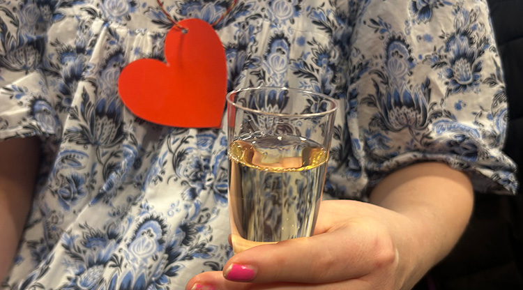 En tjej med ett hjärta runt halsen och ett glas bubbel i handen