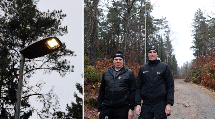 Lyktstolpe med belysning och två personer som står på ett motionsspår som är upplyst.