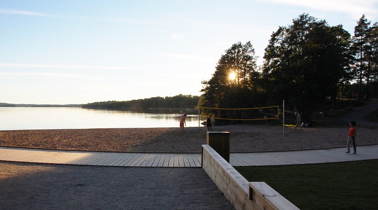 Badplats med strand intill sjö.