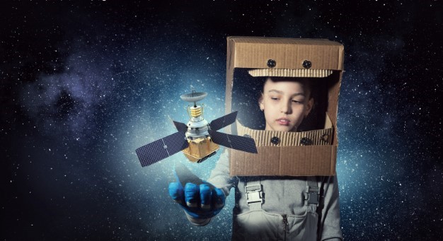 Pojke i rymddräkt håller satellit i handen