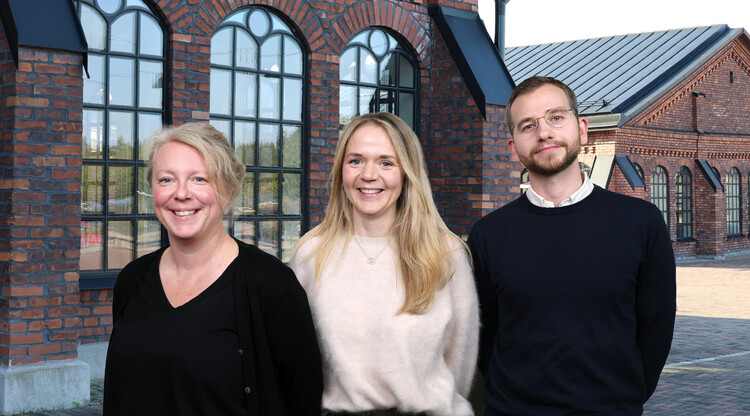 Tre personer framf&ouml;r byggnad.