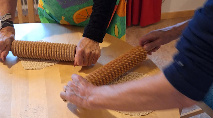 Två äldre personer som kavlar tunnbröd.