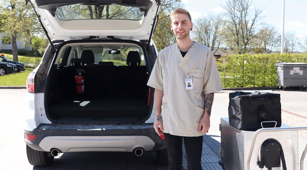 Extraresursen Rasmus står utanför en bil och är redo att börja packa in matlådor.