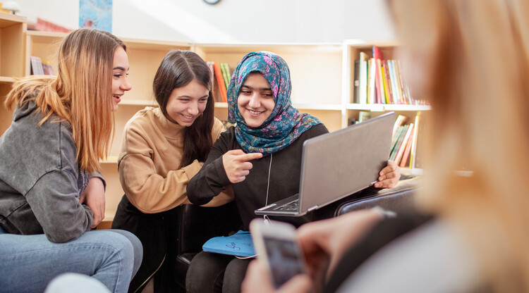 Tre elever i ett bibliotek.