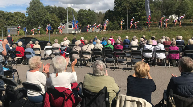 Seniorer applåderar när de kvinnliga åkarna åker förbi under Alliansloppet.