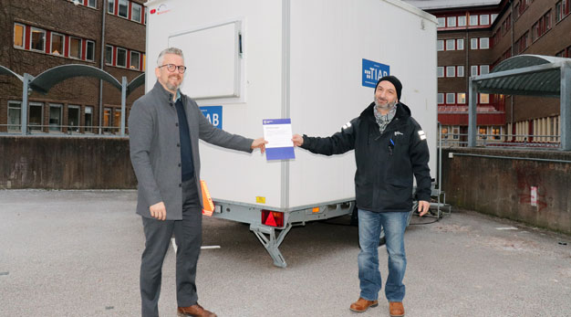 Person lämnar över ett diplom till en annan person utomhus.