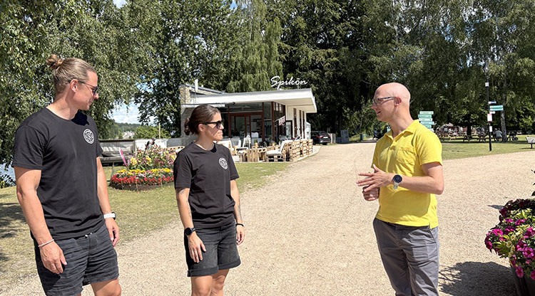 Christoffer Lundh och Michaela Sperring från Skoftebyns IF i samtal med Peter Broström, avtalsansvarig på Trollhättans stad, framför servicebyggnaden på Spikön.