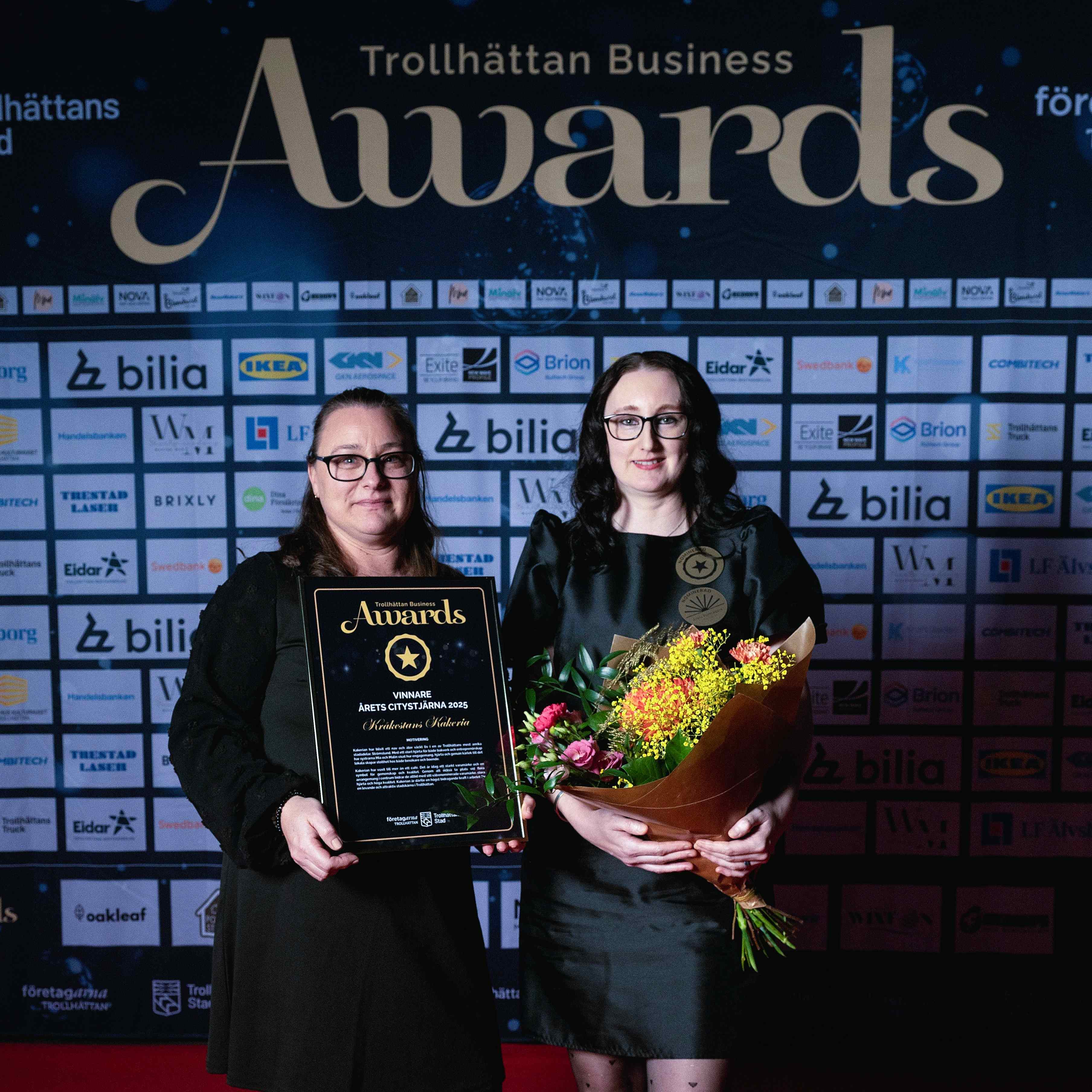 Representanter fr&aring;n Kakerian med blommor och diplom