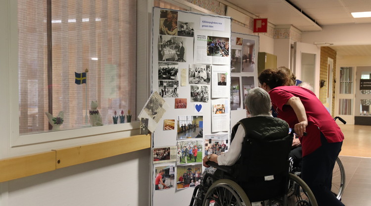 Person i rullstol och personal tittar på en fotovägg med bilder från Källstorps historia