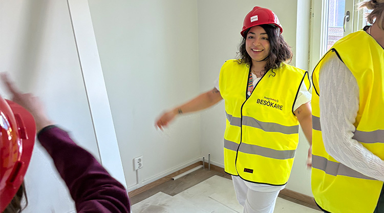 Glad kvinna med varselväst och bygghjälm