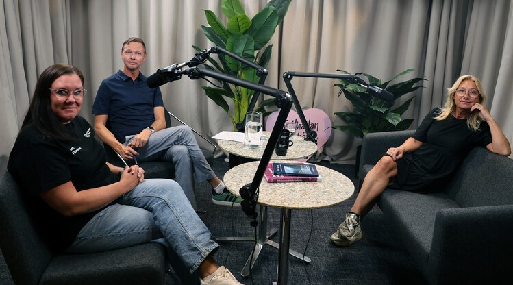 Tre personer sitter i en studio med mikrofoner.
