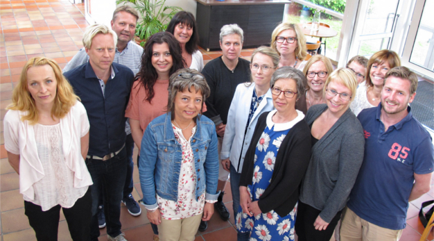 15 lärare står i en grupp och tittar upp mot fotografen.