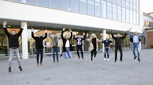 Glada representanter från Högskolan, Kraftstaden, Eidar och Trollhättans Stad gör glädjehopp framför entren till HV