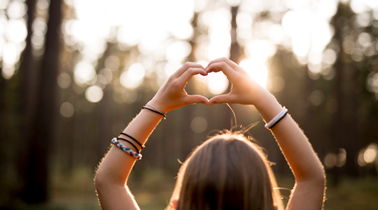 en flicka håller upp händerna och bildar en hjärt-form