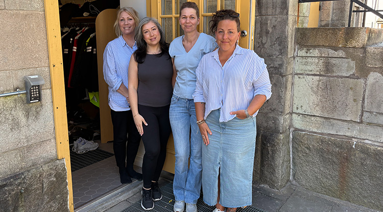 Fyra kvinnor står på rad vid en öppen ytterdörr.