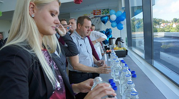 Människor som testar vatten i olika flaskor.