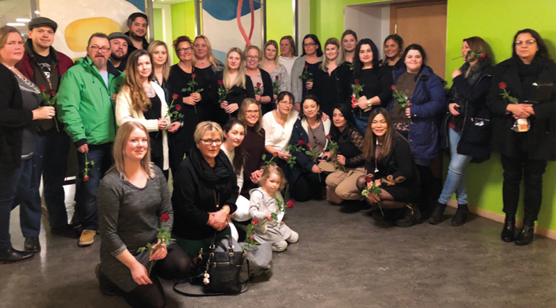 Bild på Trollhättans Stads nya undersköterskor och stödassistenter efter de färdigutbildats. Alla håller varsin röd ros.