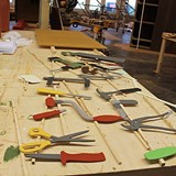 Fotografiet är en närbild över träverktyg som ska sitta inne i verkstaden. Verktygen ligger på ett skrivbord på tork. Det har bland annat skapats en hammare, kniv, pensel, skruvmejsel och borrmaskin. 