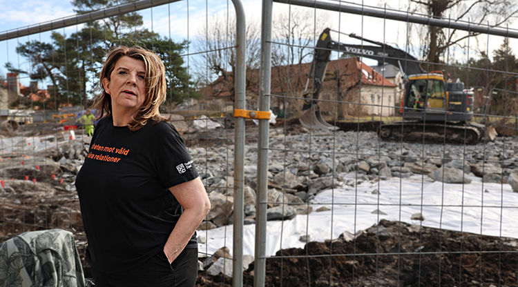 Porträtt av kvinna framför byggarbetsplats.