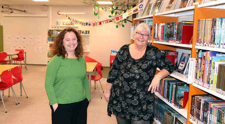 Två glada personer står inne i ett bibliotek.