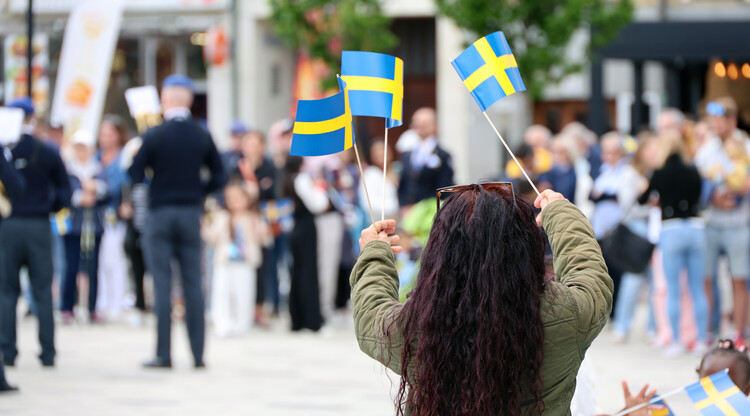 Person viftar med svenska flaggor.