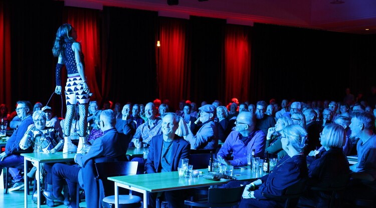 Person står på bord och sjunger inför publik.