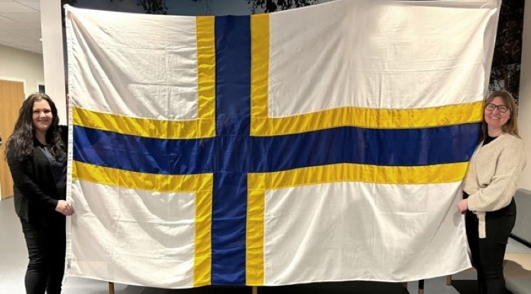 två kvinnor håller upp en stor sverigefinsk flagga