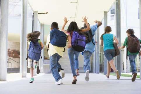 Barn sedda bakifrån, som springer i skolkorridor