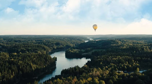 Bilden föreställer en gul luftballong i luften. Ballongen flyger över älven i Trollhättan.