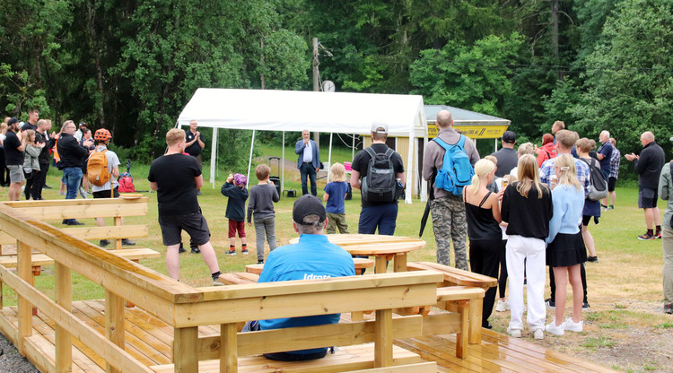 Människor samlade utomhus och lyssnar på person som håller tal.