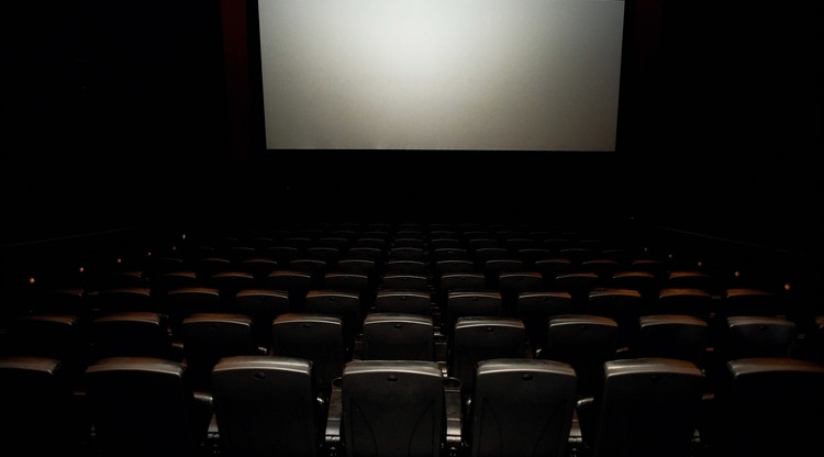 Biosalong med stolar framför filmduk.