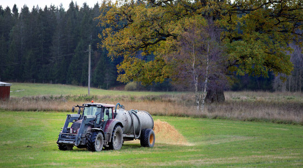 En traktor sprider gödsel på en åker.