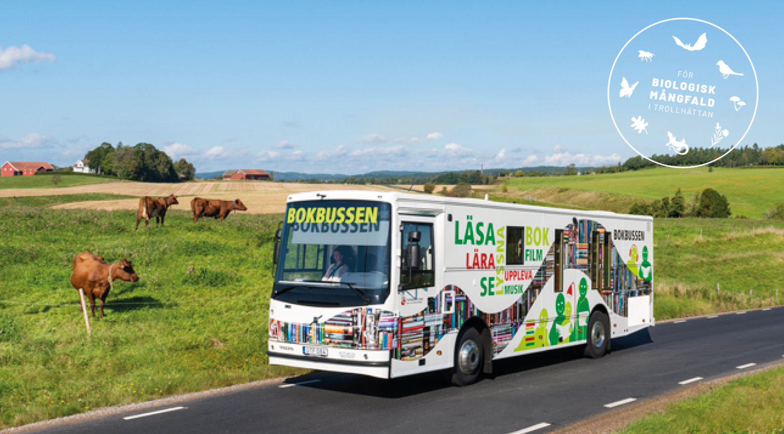 Bokbussen åker på landsväg. Symbol med texten "Biologisk mångfald i Trollhättan". 