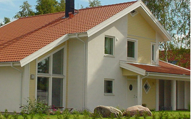 Bilden visar husets ljust gula fasad med både puts och trä som skapar en härlig kontrast.