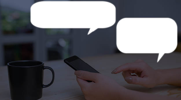 Kvinna som håller i en telefon, en kaffekopp står på bordet och två chattrutor syns.
