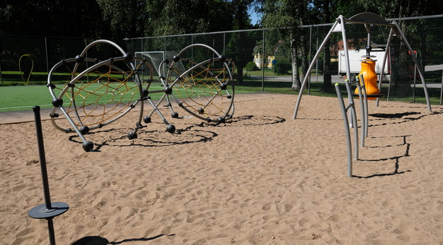 Bilden visar De Lavals aktivitetsyta. I bild till vänster syns två ställningar för klättring. I förgrunden syns ett volträcke med tre platser. Marken är sand. 