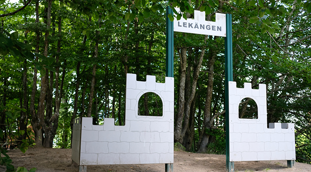 Bilden föreställer en ingång till en lekbord bestående av två väggar som liknar ett slott. Väggen är i grått och en skylt med texten lekängen pryder ingången. 