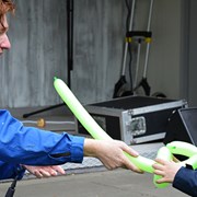 En man ger ett barn en grön ballongfigur som liknar ett svärd