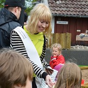 På bilden syns en kvinna som delar ut böcker till barn