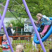 I bilden syns barn som gungar på blå/svarta kompisgungor