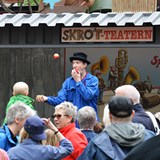 Bilden föreställer ett publikhav som tittar på en trollkarl som jonglerar med röda äpplen  