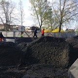Inne på lekplatsbygget jobbar arbetare med markförberedelser. 