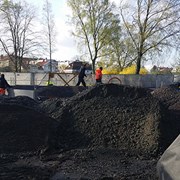 Inne på lekplatsbygget jobbar arbetare med markförberedelser. 