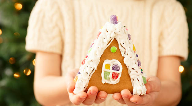 Tjej som håller ett pepparkakshus i händerna. 