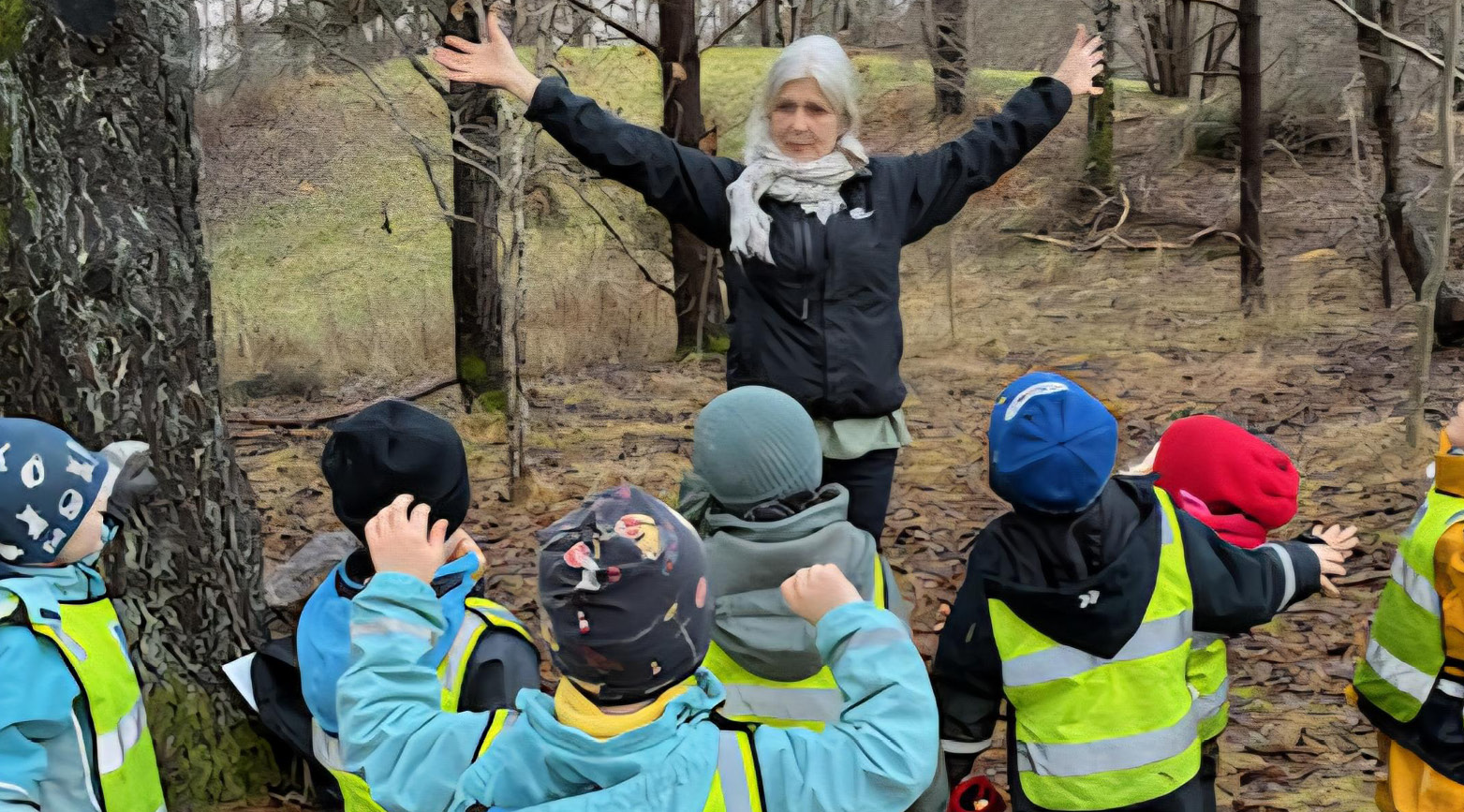 Kvinna som gestikulerar framför en grupp barn i skogen. 